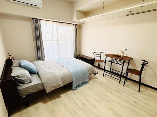 a bedroom with a bed and a table and a window at まるまる貸切のアパートマンション名古屋駅エリアから1駅 in Nagoya