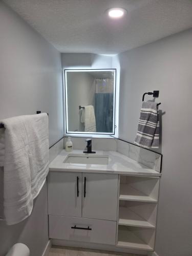 a bathroom with a sink and a mirror and towels at Exclusive Suite in Edmonton in Edmonton