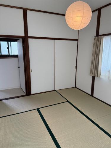 an empty room with white walls and two large windows at 宿 Oshikiri01 in Shibushi