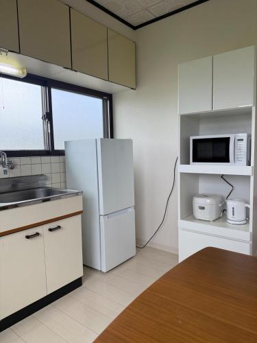 a kitchen with a white refrigerator and a microwave at 宿 Oshikiri01 in Shibushi