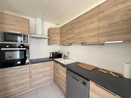 une cuisine avec des armoires en bois et un comptoir noir dans l'établissement Maison aux Sables-d'Olonne avec jardin, 4 couchages - FR-1-197-627, à Les Sables-dʼOlonne