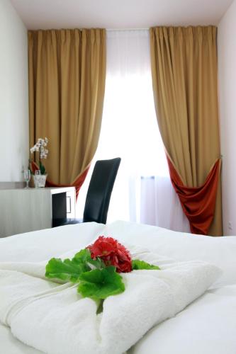 a red rose sitting on a white bed at Amso Residence in Sibiu