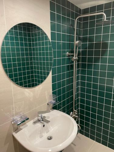 a green tiled bathroom with a sink and a mirror at Londonker in Busan