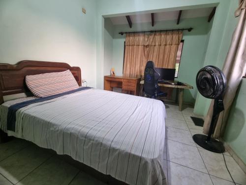 Schlafzimmer mit einem Bett und einem Schreibtisch mit einem Ventilator in der Unterkunft Habitación para teletrabajo in Santa Cruz de la Sierra