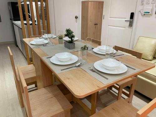 a wooden table with plates and silverware on it at Supreme Luxury 2BR Condo - Azure Urban Resort Residences near Manila Airport in Manila