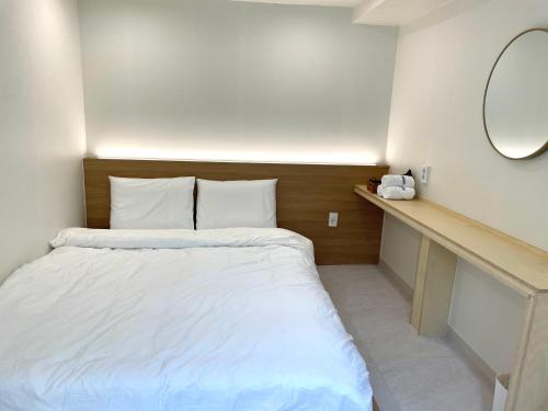 a bedroom with a white bed and a mirror at Londonker in Busan