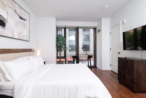 a white bedroom with a large bed and a table at Back-Bay Upscale Central Condo Rooftop & Parking in Boston