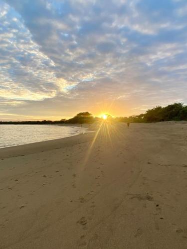 a beach with the sun setting in the distance at La Casita 4BR Private Paradise with Pool in La Garita