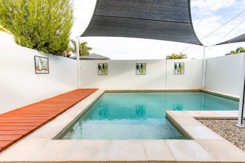 a swimming pool with a wooden deck and a white wall at Golden Beach Family Home with Pool in Golden Beach