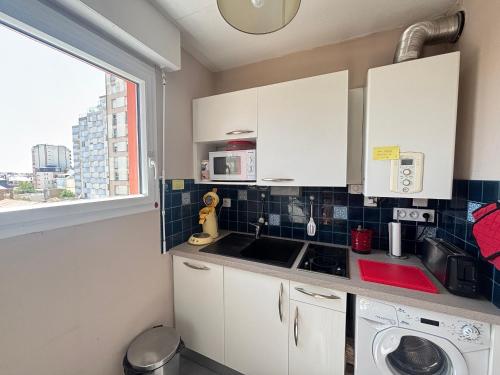 Elle comprend une petite cuisine avec des placards blancs et une fenêtre. dans l'établissement Appartement 2 pièces accès direct plage, parking privé - FR-1-197-604, à Les Sables-dʼOlonne