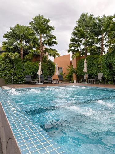 a swimming pool with palm trees in a resort at Rachabhura Hotel in Ratchaburi