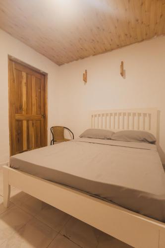 a bedroom with a bed and a wooden door at La Chamba Surf House in Santa Catalina