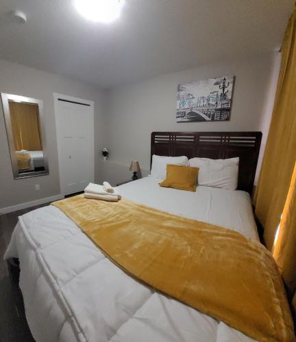 a bedroom with a large bed with a yellow blanket on it at Spacious Basement Suite NW Calgary- 1bedroom 2 guest maximum in Calgary