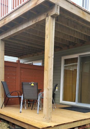 a patio with two chairs and a table on a deck at Spacious Basement Suite NW Calgary- 1bedroom 2 guest maximum in Calgary