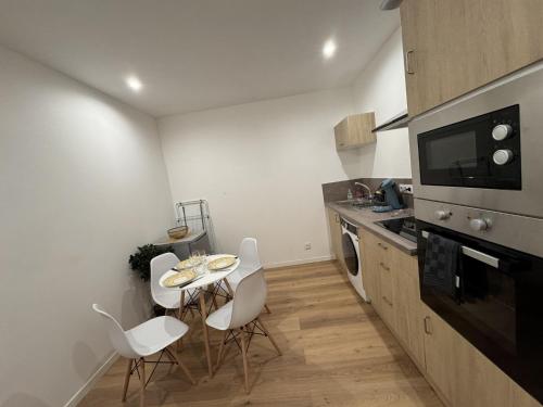 une cuisine avec une table et des chaises blanches dans l'établissement Cozy Urban Nest Near Le Mans, à Écommoy