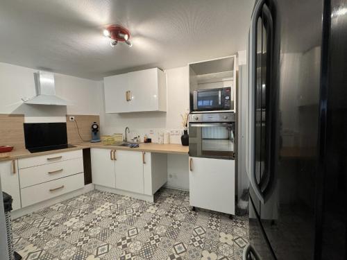 une cuisine avec des armoires blanches et un réfrigérateur en acier inoxydable dans l'établissement Apartment in Écommoy near Le Mans Circuit, à Écommoy