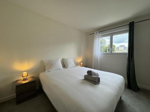 une chambre avec un grand lit blanc avec une fenêtre dans l'établissement Apartment near Le Mans Circuit, au Mans