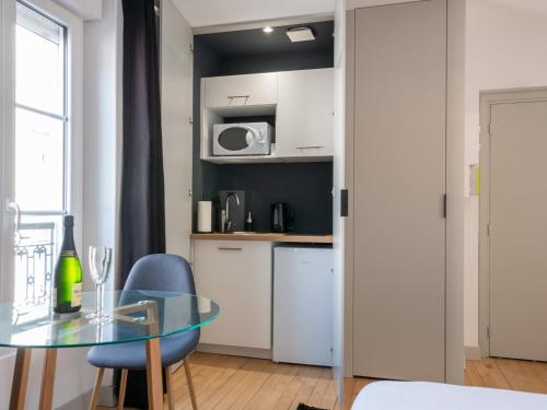 une petite cuisine avec une table en verre et des chaises bleues dans l'établissement Apartment in Le Mans with Private Sauna, au Mans