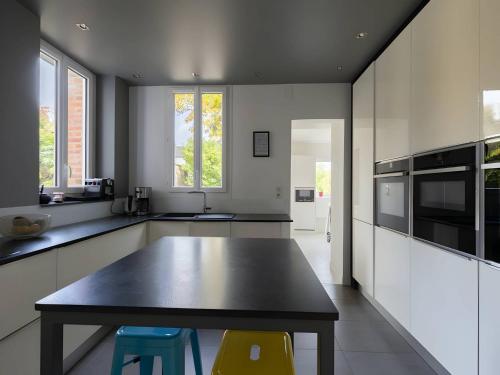 une cuisine avec une table et deux tabourets dans l'établissement High-End Villa Stay in Le Mans, au Mans