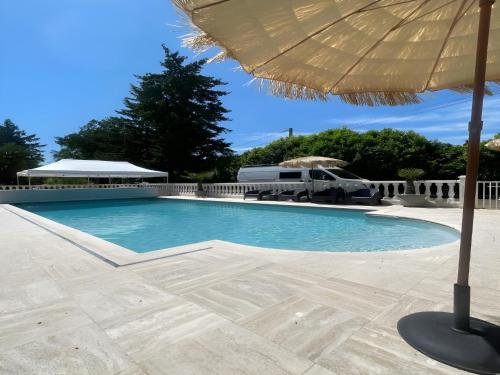 une grande piscine avec un parasol et un camion dans l'établissement Spacious Poolside Retreat Near Le Mans, à Spay