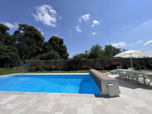 - une piscine avec un banc et un parasol dans l'établissement Château in Sarthe with Heated Pool, à Dangeul