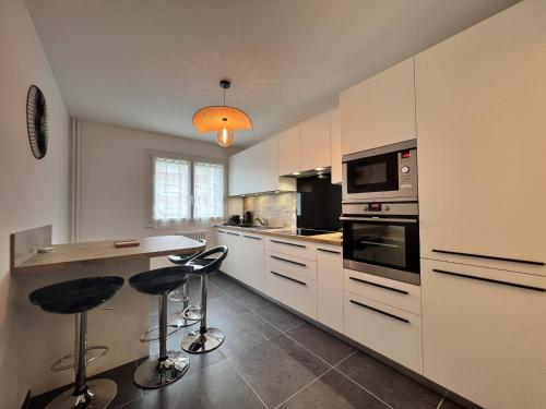 une cuisine avec des armoires blanches et un comptoir avec des tabourets dans l'établissement Apartment in Le Mans with Retro-Chic Style, au Mans
