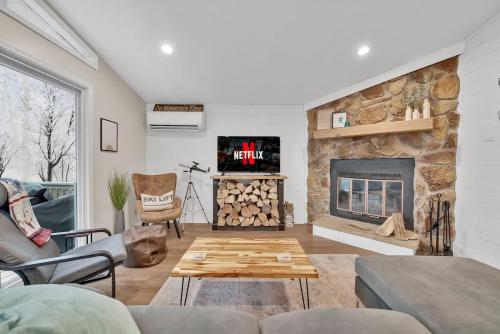 a living room with a stone fireplace with a tv at A Refined Retreat in Lackawaxen