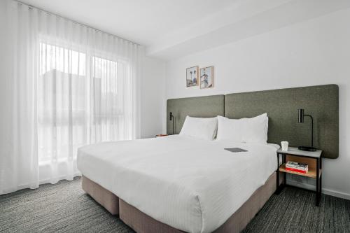 a bedroom with a large bed and a large window at Quest Moonee Valley in Melbourne