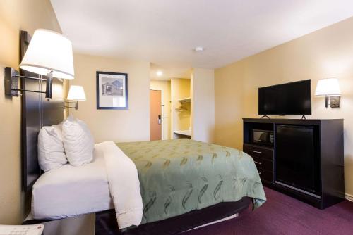 a hotel room with a bed and a flat screen tv at Quality Inn Airport in Boise