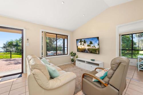 a living room with two chairs and a tv at Bayview Cottage Waterfront Soldiers Point in Soldiers Point