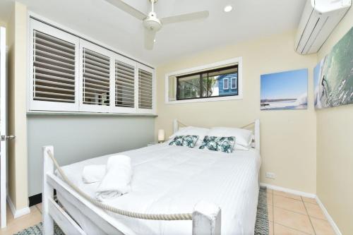 a bedroom with a white bed and two windows at Bayview Cottage Waterfront Soldiers Point in Soldiers Point