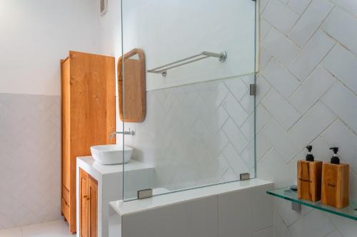 a bathroom with a sink and a glass shower at Comoda Seminyak in Seminyak
