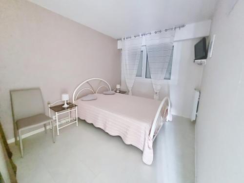 une chambre blanche avec un lit et une chaise dans l'établissement Appartement 4 personnes près de la mer avec terrasse et parking - FR-1-746-34, à Courseulles-sur-Mer
