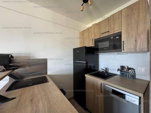 - une cuisine avec des appareils noirs et des armoires en bois dans l'établissement Location cosy avec Wi-Fi et parking couvert aux Angles - FR-1-295-208, aux Angles