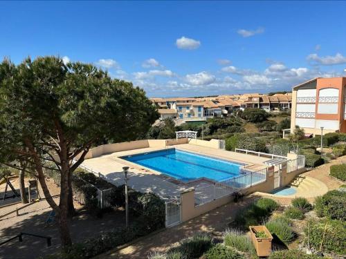 une grande piscine dans une cour avec un arbre dans l'établissement Appt 3 pièces, 6 couchages avec balcon et vue mer - FR-1-229D-164, à Fleury