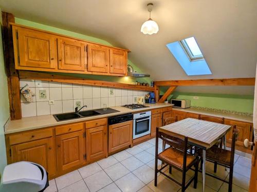 une cuisine avec des armoires en bois et une table à l'intérieur dans l'établissement Gîte du Champ du Bois : Confort au cœur des Vosges - FR-1-589-820, à Le Tholy