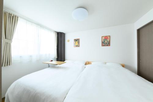 two beds in a room with a window at CleanNest Hokkaido Chitose in Chitose