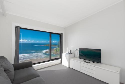 a living room with a tv and a large window at Pacific Hotel Yamba in Yamba