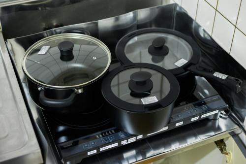 a black stove top with two pots on it at CleanNest Hokkaido Chitose in Chitose