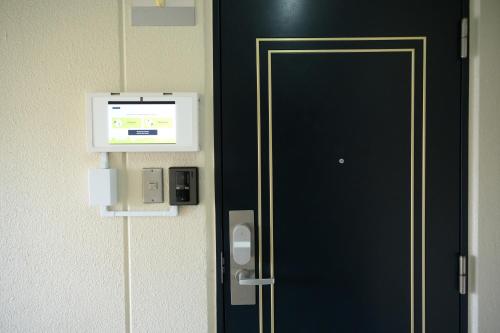 a black door with a pay phone on a wall at CleanNest Hokkaido Chitose in Chitose