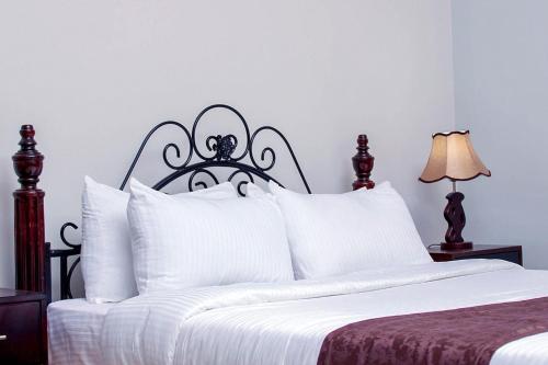 un letto bianco con testiera nera e cuscini bianchi di Grafo a Kampala