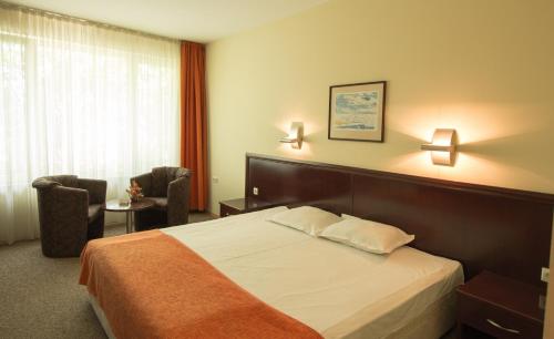 a hotel room with a bed and two chairs at Hotel Divesta - self check in in Varna City