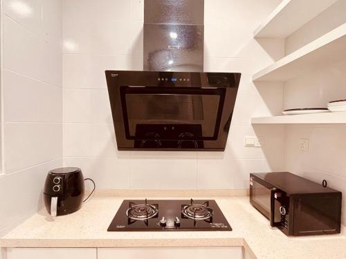 a kitchen with a stove and a microwave at Cozy Villa - Private Pool, 5BR, KTV, BBQ, PS5 just 3 Mins to Batu Ferringhi Beach! in Batu Ferringhi