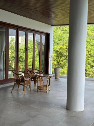 a patio with chairs and a table and windows at Villa Ayu Lombok in Kuta Lombok