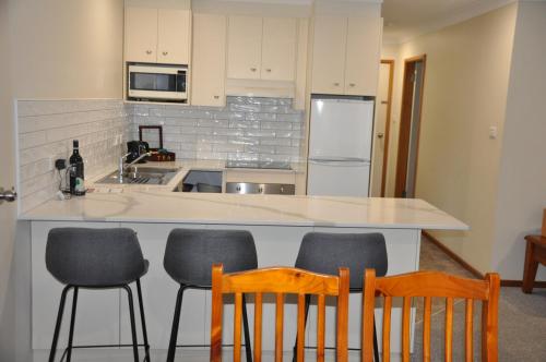 a kitchen with a counter with four chairs in it at Pokolbin Village Estate in Pokolbin