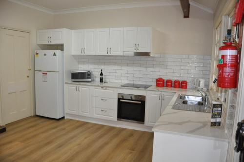 a kitchen with white cabinets and a white refrigerator at Pokolbin Village Estate in Pokolbin