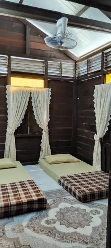 a bedroom with two beds and a ceiling fan at Rumah Kayu Masjid Zahir in Alor Setar
