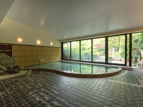a large swimming pool in a building with windows at Livemax Resort Yuhigaura Kitu Onsen in Kyotango