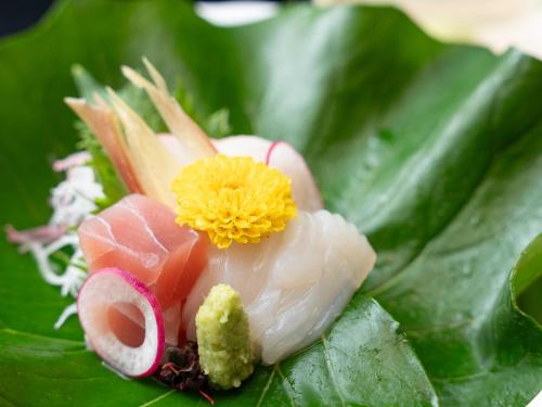 a pile of sushi with a yellow flower on top at Livemax Resort Yuhigaura Kitu Onsen in Kyotango
