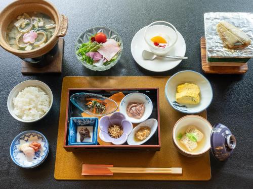 a table with plates of food and bowls of food at Livemax Resort Yuhigaura Kitu Onsen in Kyotango